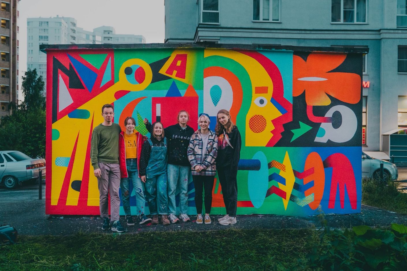 Студентка Школы дизайна Анастасия Вокина (вторая справа) на фоне своей работы для фестиваля STENOGRAFFIA (2022 год)